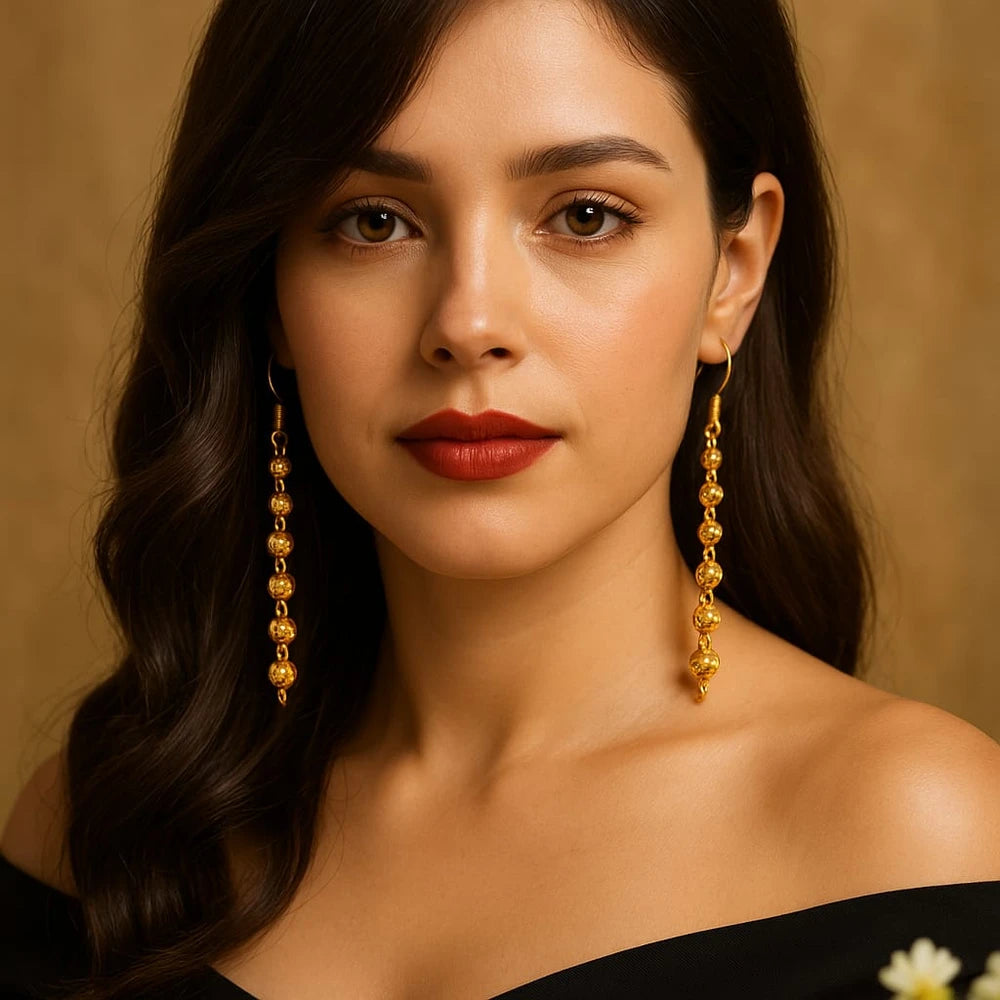 Outdoor shot of Zhome long gold ball-chain Sui-Dhaga earrings hanging on a tree branch – made by Sandeep Singh